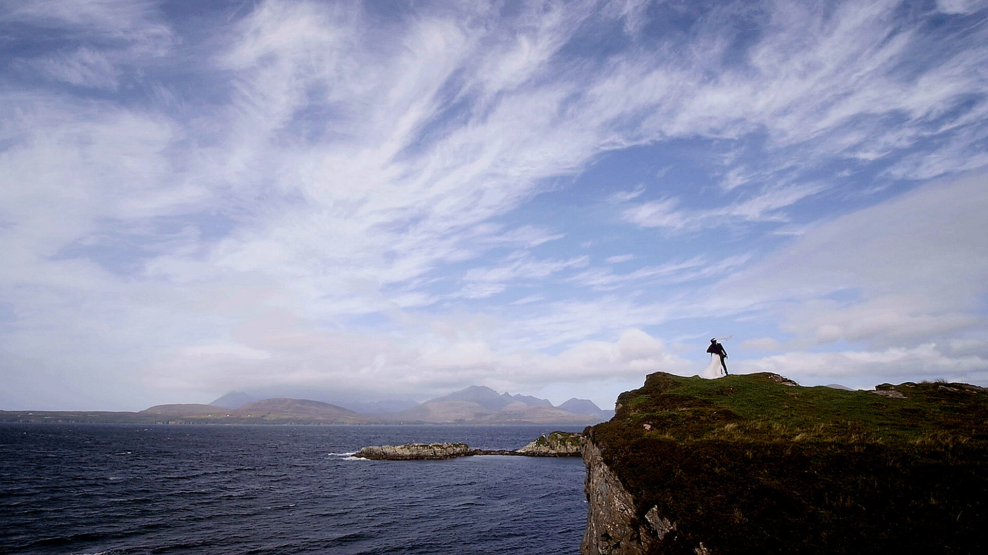 Aerial view of an elopement couple exploring the historic ruins and cliff edges of Dunscaith Castle on the Isle of Skye, by Isle of Skye Elopement Videographer, Thistle Production