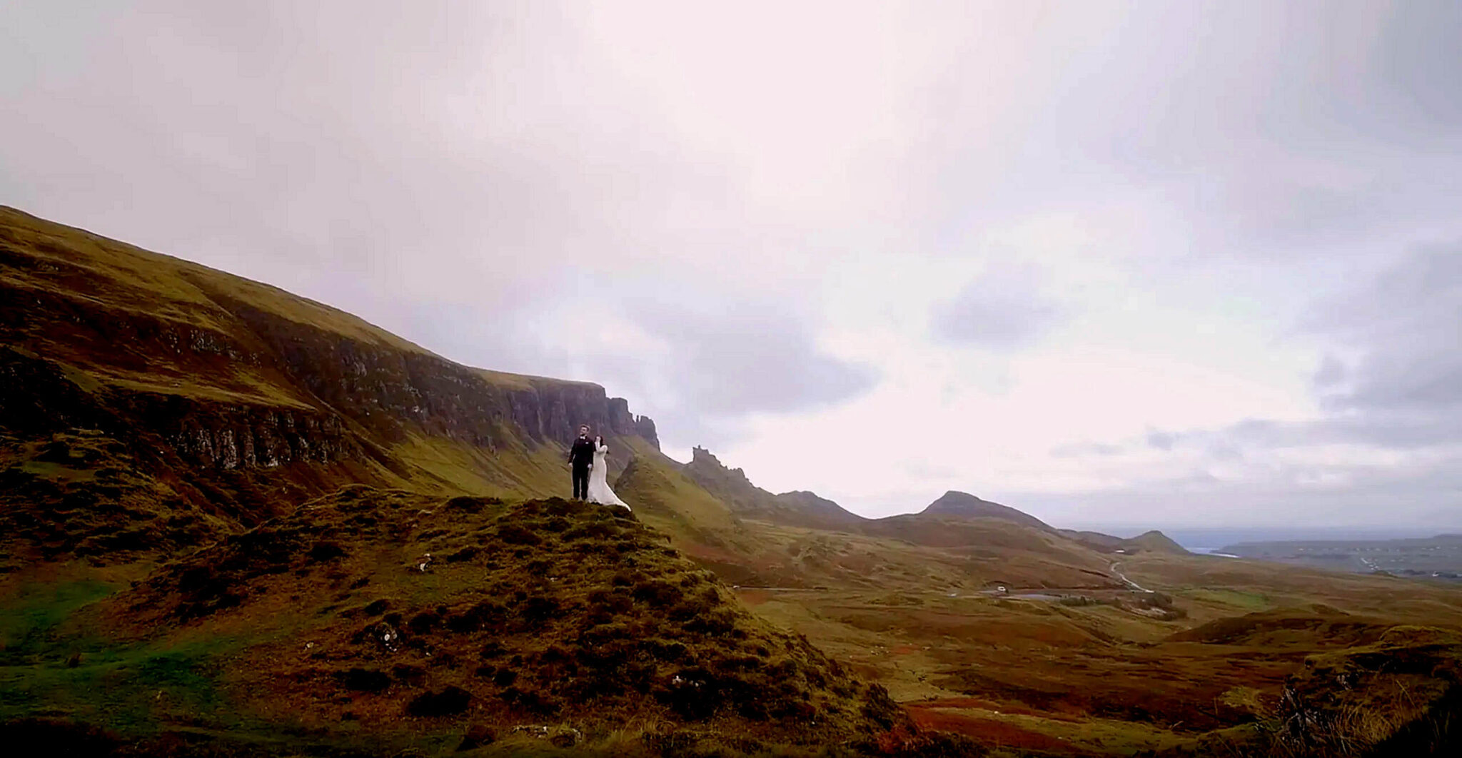 Cinematic drone shot of an elopement couple at the Quiraing on the Isle of Skye, featuring rugged Highland landscapes from Glencoe to Eilean Donan Castle.